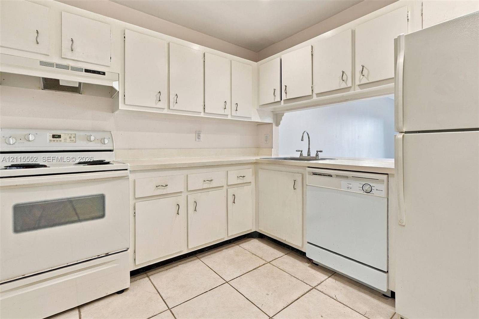 7805 Camino Real, #H-220, Miami, FL 33143 Kitchen featuring white cabinetry, solid-surface countertops, tile flooring, and integrated white appliances including a range, dishwasher, and refrigerator
