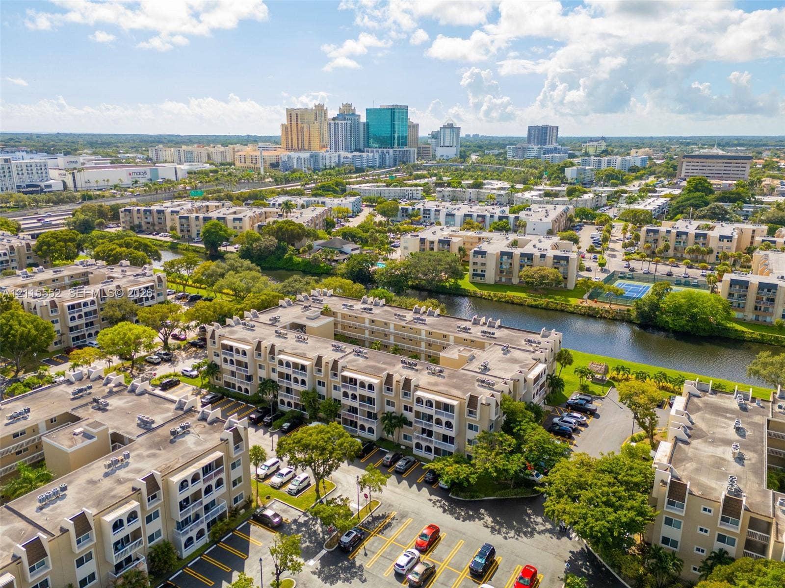 7805 Camino Real, #H-220, Miami, FL 33143 Multi-story residential complex featuring beige stucco facades, arched architectural detailing, balconies, and on-site surface parking