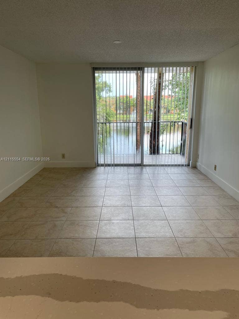 10781 Cleary Boulevard, #210, Plantation, Plantation, FL 33324 Neutral tile flooring, sliding glass door, and exterior balcony featuring water scenery