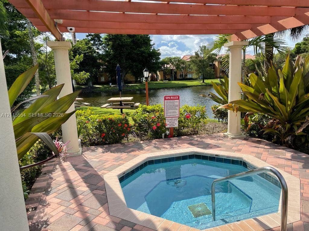 10781 Cleary Boulevard, #210, Plantation, Plantation, FL 33324 Outdoor spa featuring a concrete paver deck, wooden pergola with structural columns, and metallic handrail