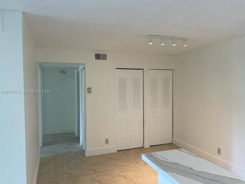 10781 Cleary Boulevard, #210, Plantation, Plantation, FL 33324 Interior space featuring tile flooring, dual white louvered closet doors, and a linear track lighting fixture