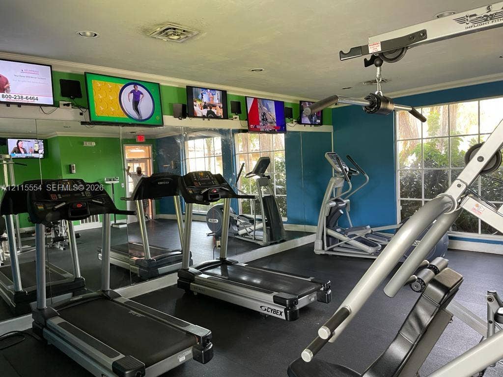 10781 Cleary Boulevard, #210, Plantation, Plantation, FL 33324 Fitness room featuring mirrored walls, rubberized flooring, and multiple wall-mounted television displays