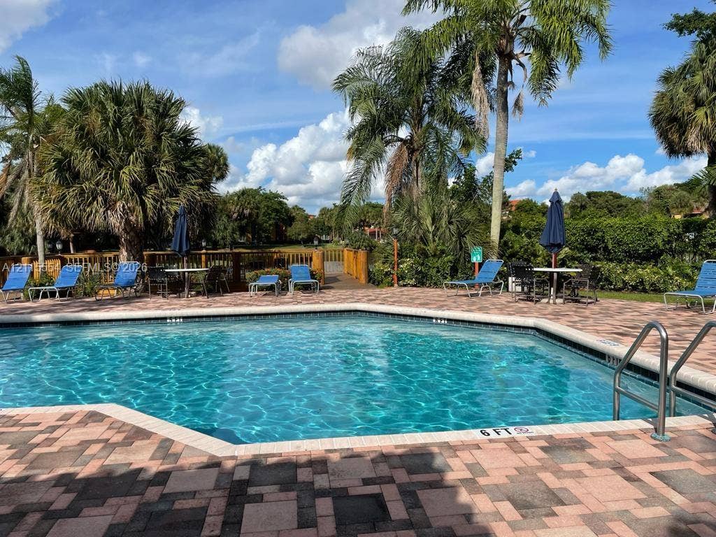 10781 Cleary Boulevard, #210, Plantation, Plantation, FL 33324 In-ground swimming pool with stone paver decking, metal entry rails, and surrounding mature palm trees