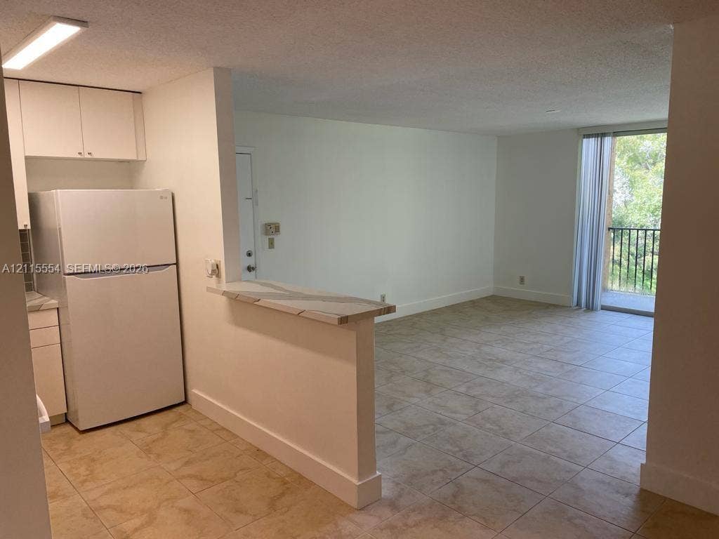 10781 Cleary Boulevard, #210, Plantation, Plantation, FL 33324 Kitchen featuring white cabinetry and a pass-through counter, tile flooring throughout, and sliding glass doors leading to a balcony