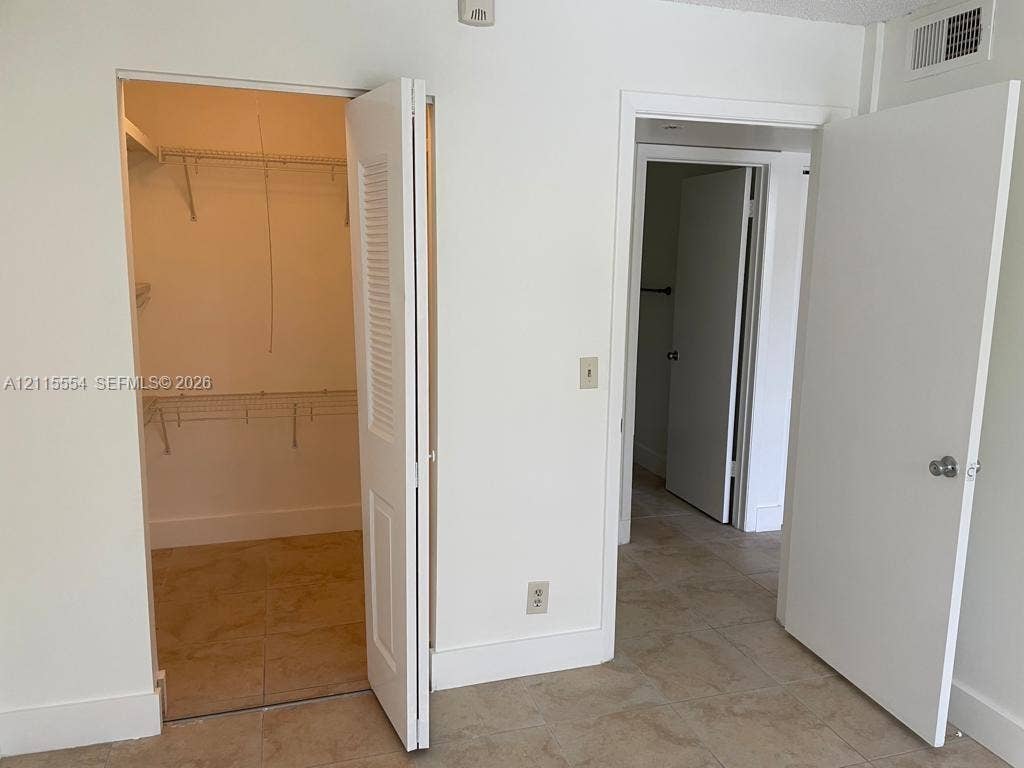10781 Cleary Boulevard, #210, Plantation, Plantation, FL 33324 Interior space featuring large-format tile flooring, a walk-in closet with built-in wire shelving, and bi-fold closet doors