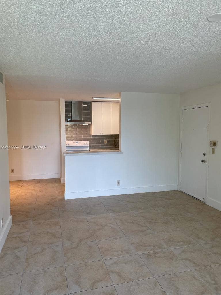 10781 Cleary Boulevard, #210, Plantation, Plantation, FL 33324 Kitchen featuring white cabinetry, a neutral subway tile backsplash, stainless steel range hood, and tile flooring