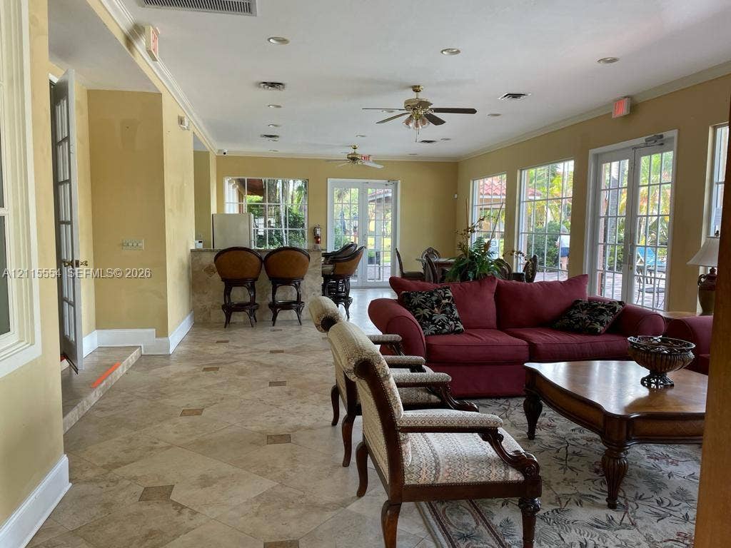 10781 Cleary Boulevard, #210, Plantation, Plantation, FL 33324 Spacious room featuring tile flooring with decorative inserts, recessed lighting, ceiling fans, multiple sets of glass-paned double doors, and a built-in bar area with a stone-finish counter