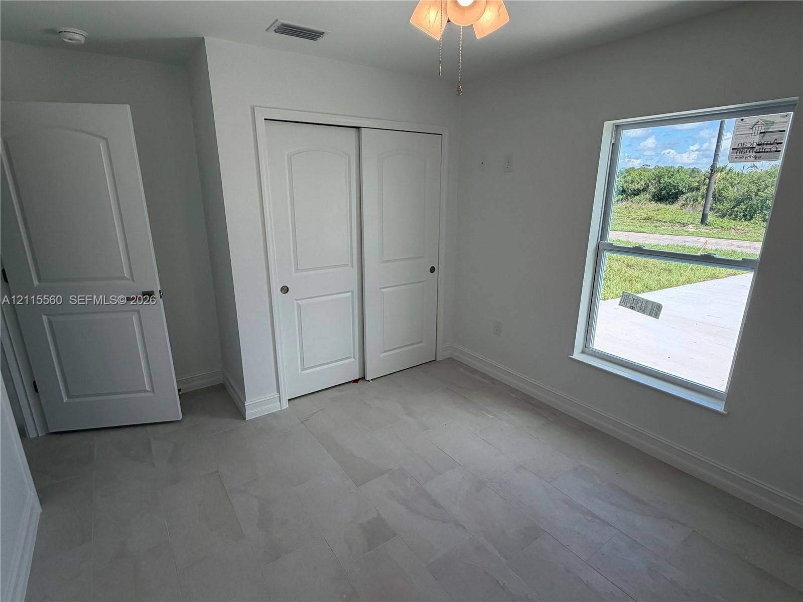105 Concord Loop, Labelle, FL 33935 Neutral-toned tile flooring, recessed ceiling light with integrated fan, multi-panel doors, and a window providing natural light