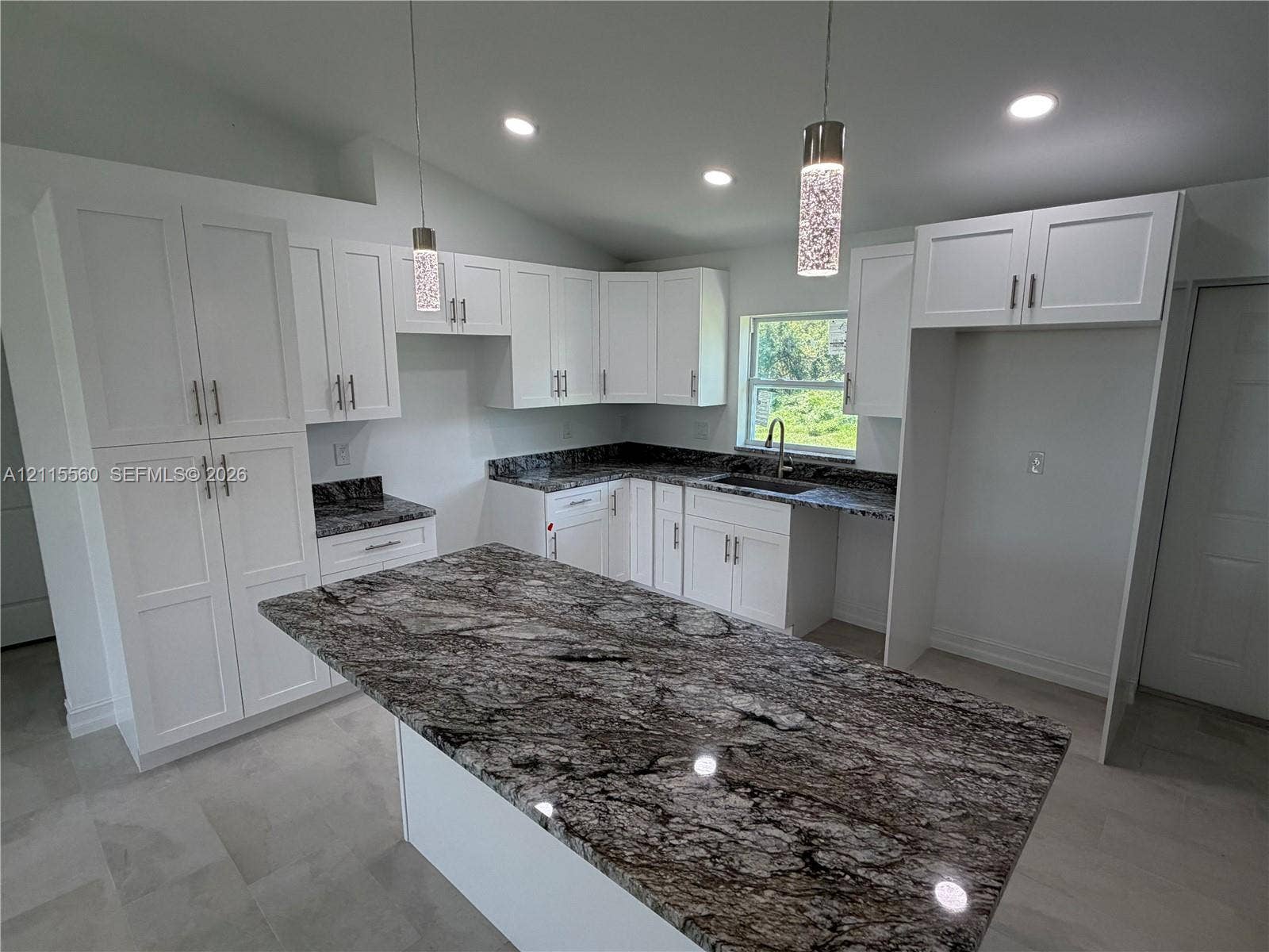 105 Concord Loop, Labelle, FL 33935 Kitchen featuring white shaker-style cabinetry, dark patterned stone countertops, a central island, recessed lighting, and dual textured glass pendant lights