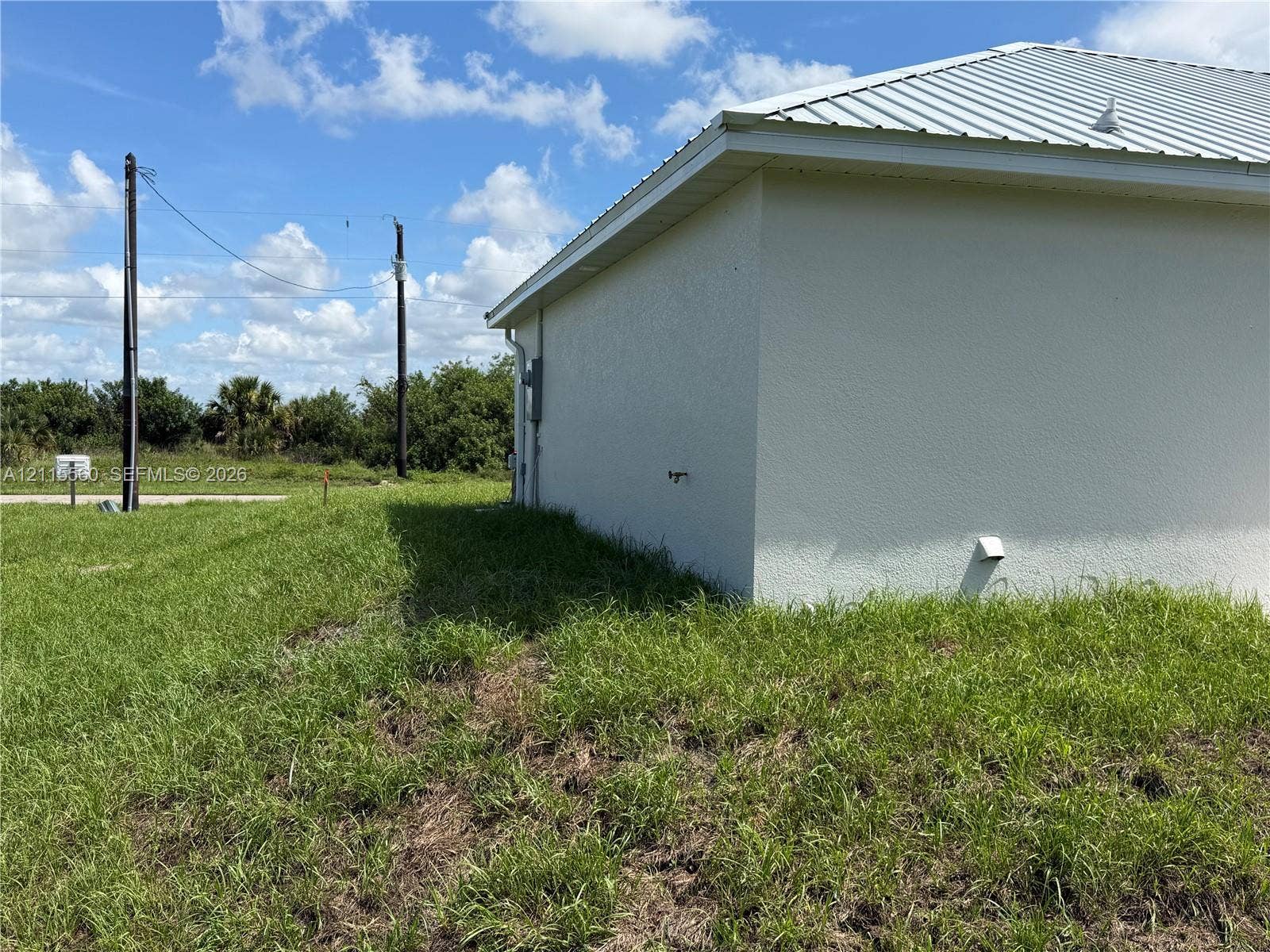105 Concord Loop, Labelle, FL 33935 Stucco exterior featuring a metal roof and an expansive lawn