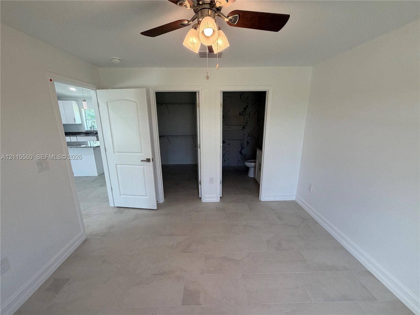 105 Concord Loop, Labelle, FL 33935 Neutral-toned tile flooring, three-panel interior door, ceiling fan with glass-shaded light fixture, and two separate interior entry points