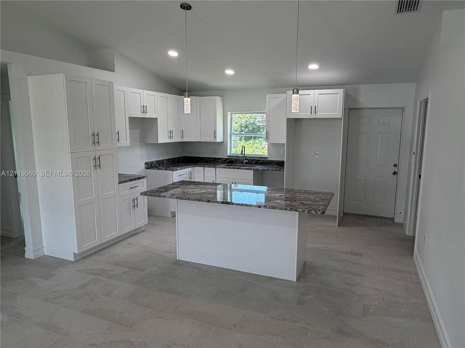 105 Concord Loop, Labelle, FL 33935 Kitchen featuring white cabinetry, patterned stone-surface countertops, central island, pendant lighting, and tile flooring