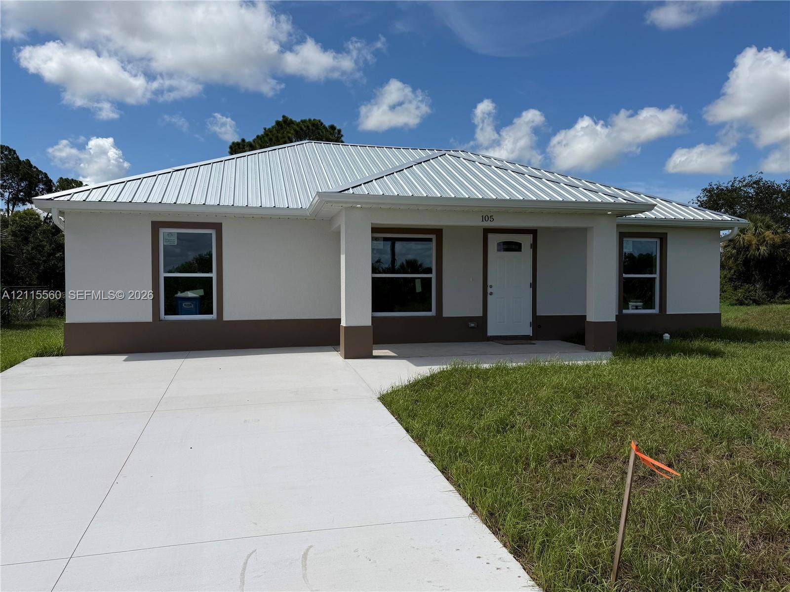 105 Concord Loop, Labelle, FL 33935 Single-story exterior featuring a metal roof, stucco finish, covered entryway, and a concrete driveway