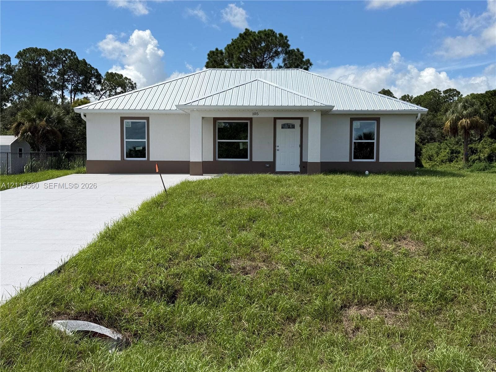 105 Concord Loop, Labelle, FL 33935 Single-story exterior featuring a metal roof, stucco siding, a covered entryway, and a concrete driveway