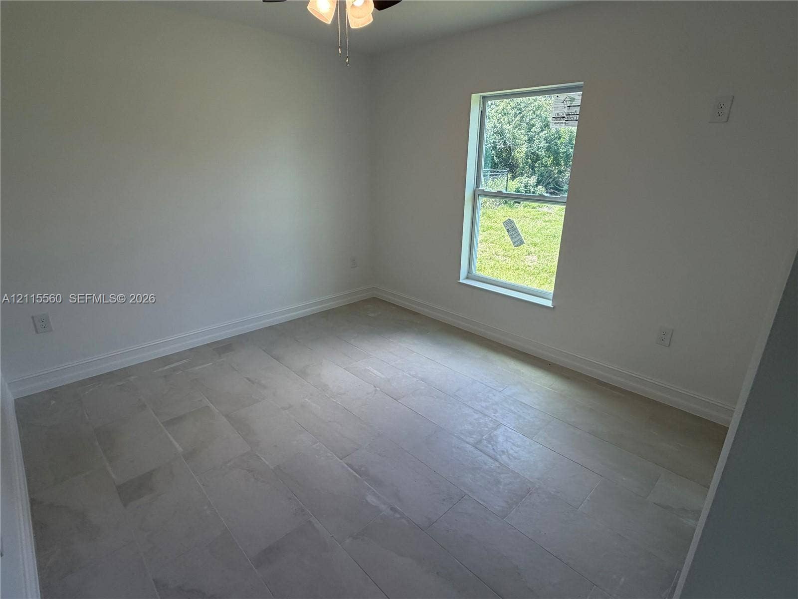 105 Concord Loop, Labelle, FL 33935 Neutral-toned tile flooring, light-colored walls, single-pane window, and a ceiling-mounted light fixture