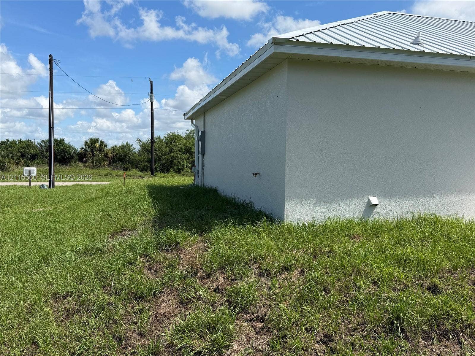 105 Concord Loop, Labelle, FL 33935 Exterior side profile featuring a metal roof and stucco siding