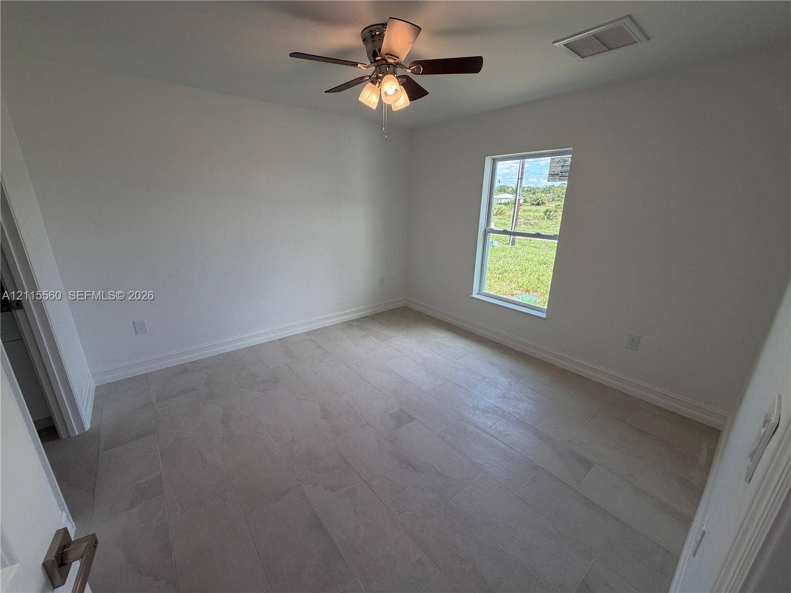 105 Concord Loop, Labelle, FL 33935 Neutral-toned tile flooring, multi-light ceiling fan, and window featuring exterior natural lighting