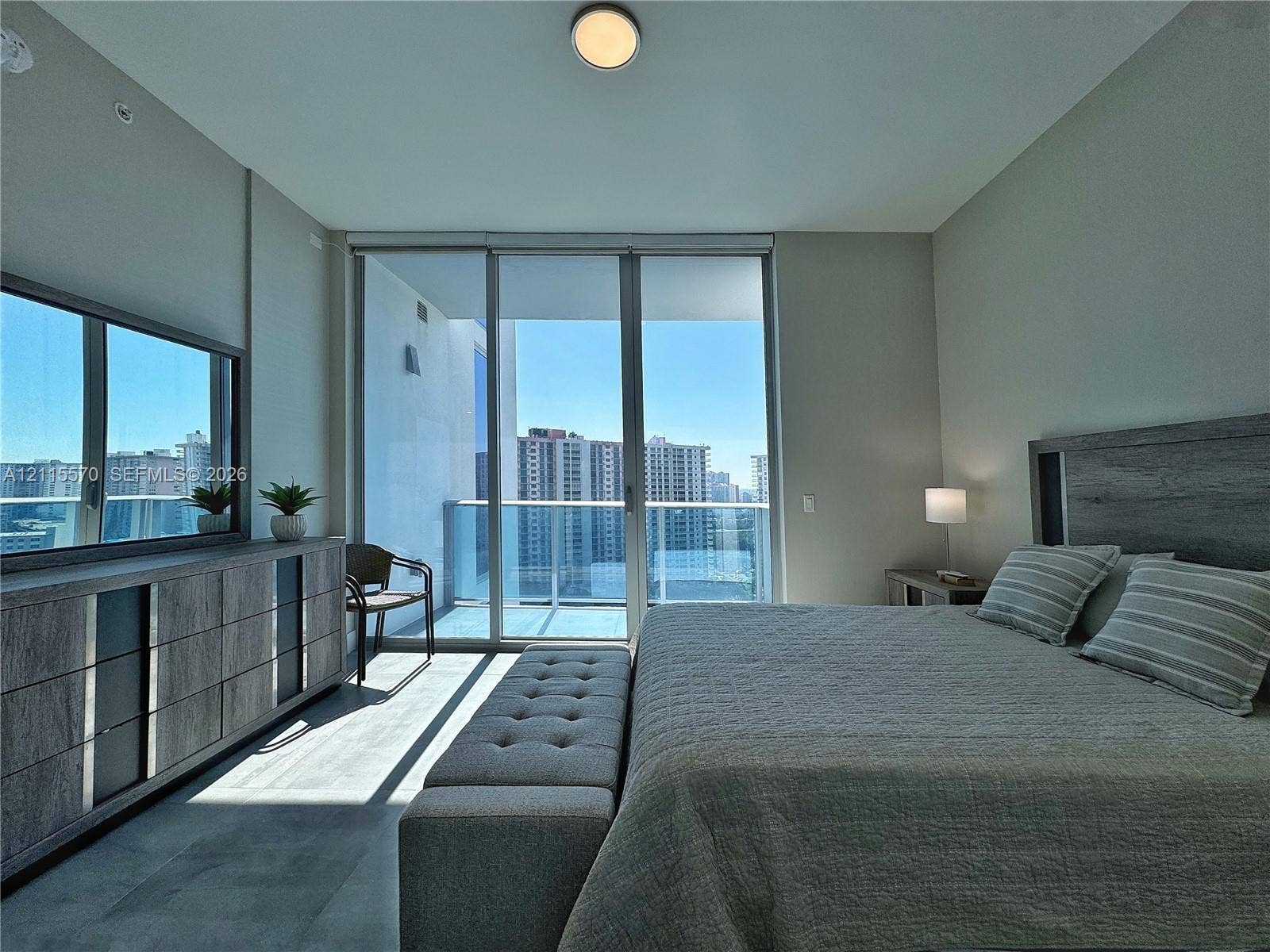 17550 Collins Avenue, #1401, Sunny Isles Beach, Sunny Isles Beach, FL 33160 Floor-to-ceiling glass sliding doors, private balcony, wood-finish flooring, and flush-mount overhead lighting