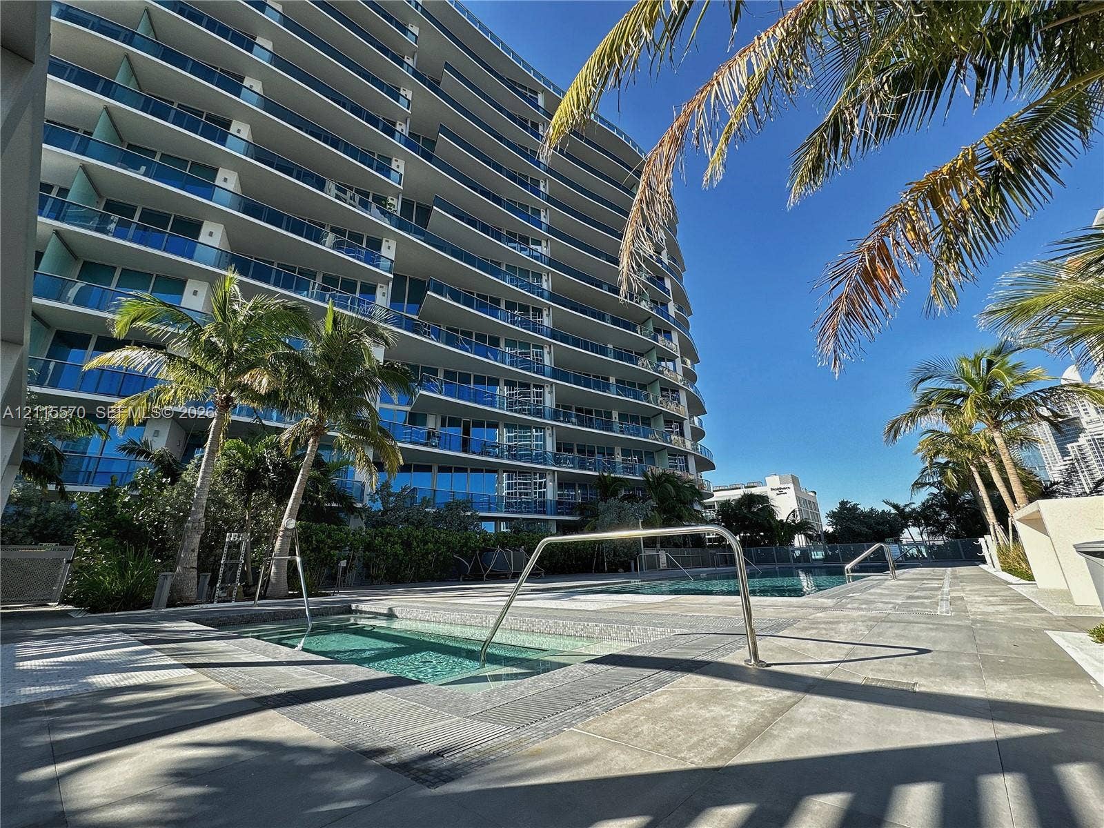 17550 Collins Avenue, #1401, Sunny Isles Beach, Sunny Isles Beach, FL 33160 High-rise exterior with glass-railed balconies, ground-level pool, tiled deck, and built-in hot tub