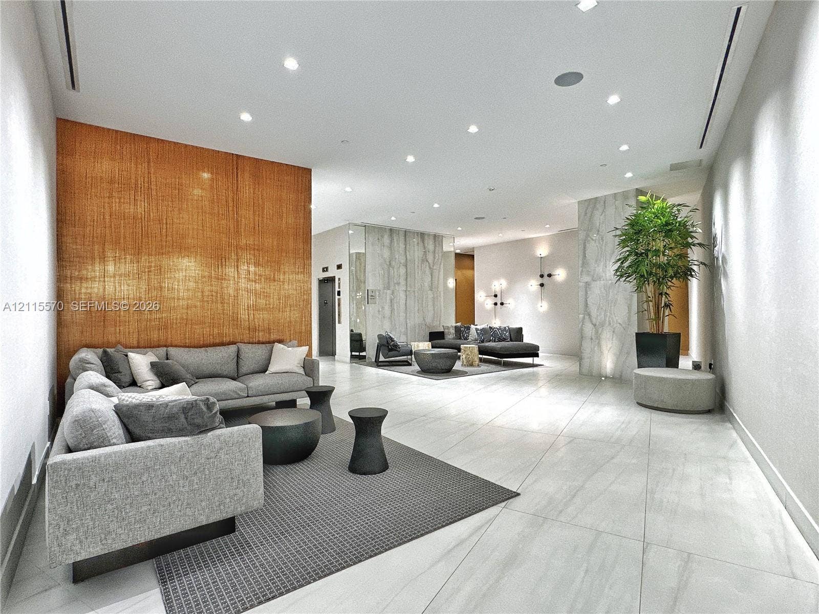17550 Collins Avenue, #1401, Sunny Isles Beach, Sunny Isles Beach, FL 33160 Large-format stone tile flooring, textured wood-paneled accent wall, stone-clad structural pillars, recessed ceiling lighting, and multi-arm geometric wall sconces