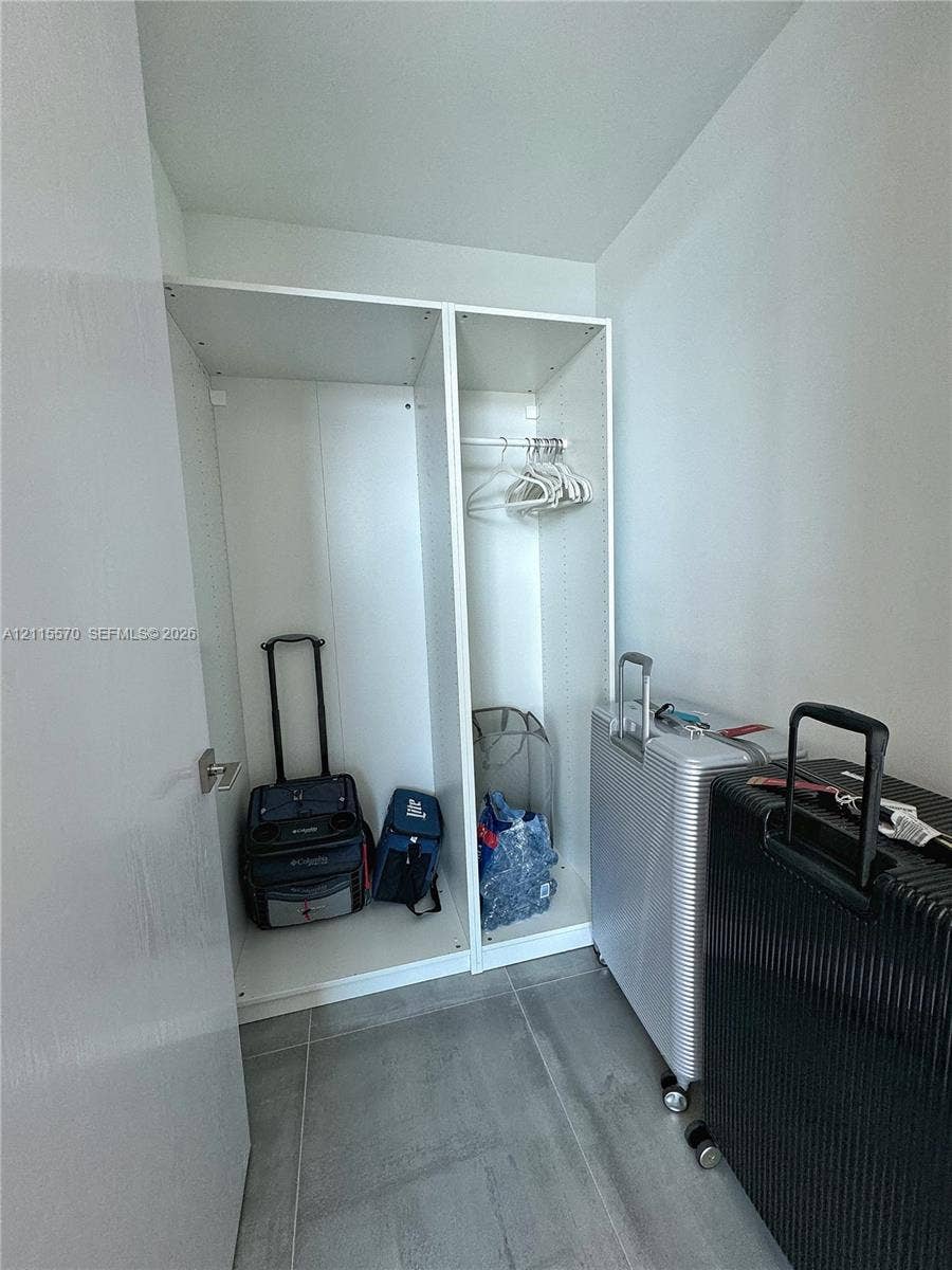 17550 Collins Avenue, #1401, Sunny Isles Beach, Sunny Isles Beach, FL 33160 Built-in white storage cabinetry featuring adjustable shelving and a hanging rod, finished with large-format grey tile flooring