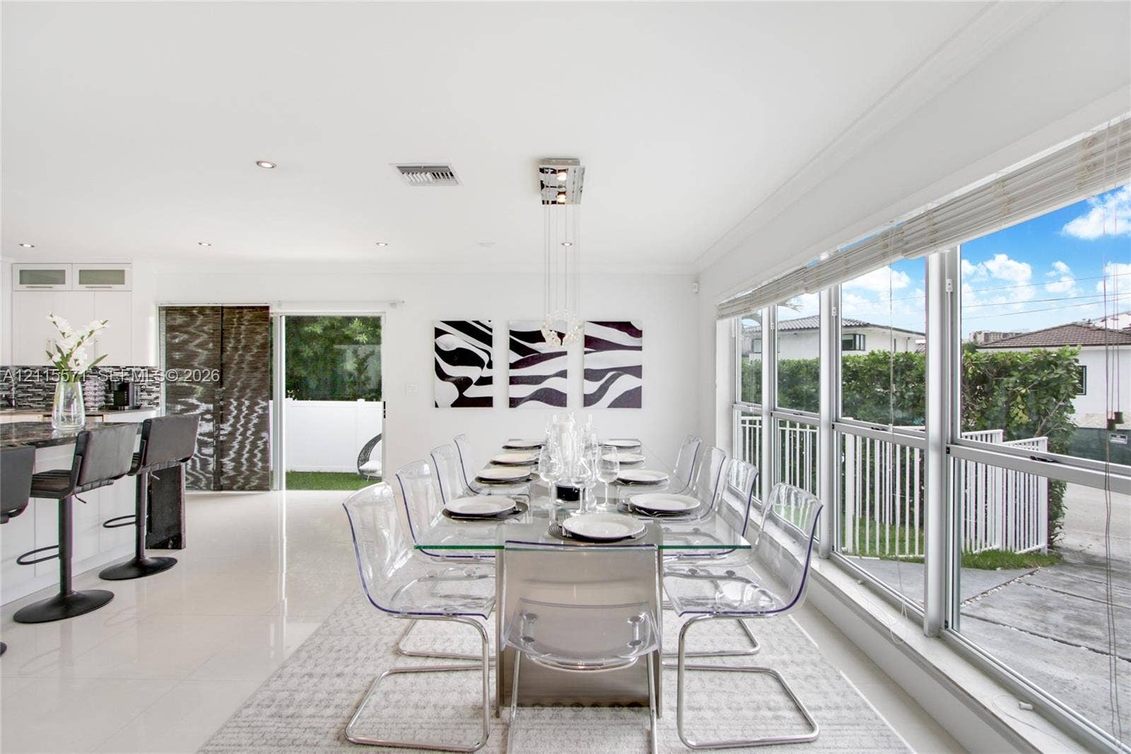 2001 NE 122nd Road, North Miami, FL 33181 Open-concept dining area featuring large windows with natural lighting, polished tile flooring, recessed lighting, a modern pendant light fixture, and white cabinetry