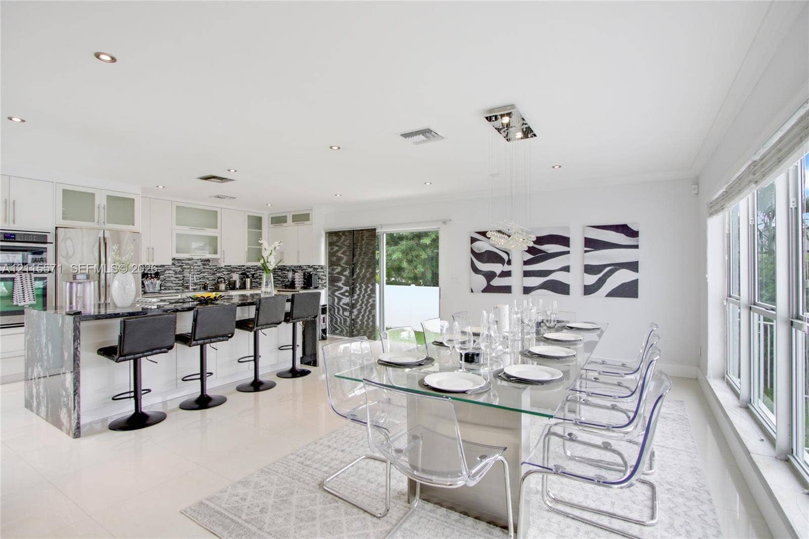 2001 NE 122nd Road, North Miami, FL 33181 Kitchen featuring white cabinetry, stone-surfaced island with waterfall edge, mosaic tile backsplash, recessed lighting, and large-format tile flooring