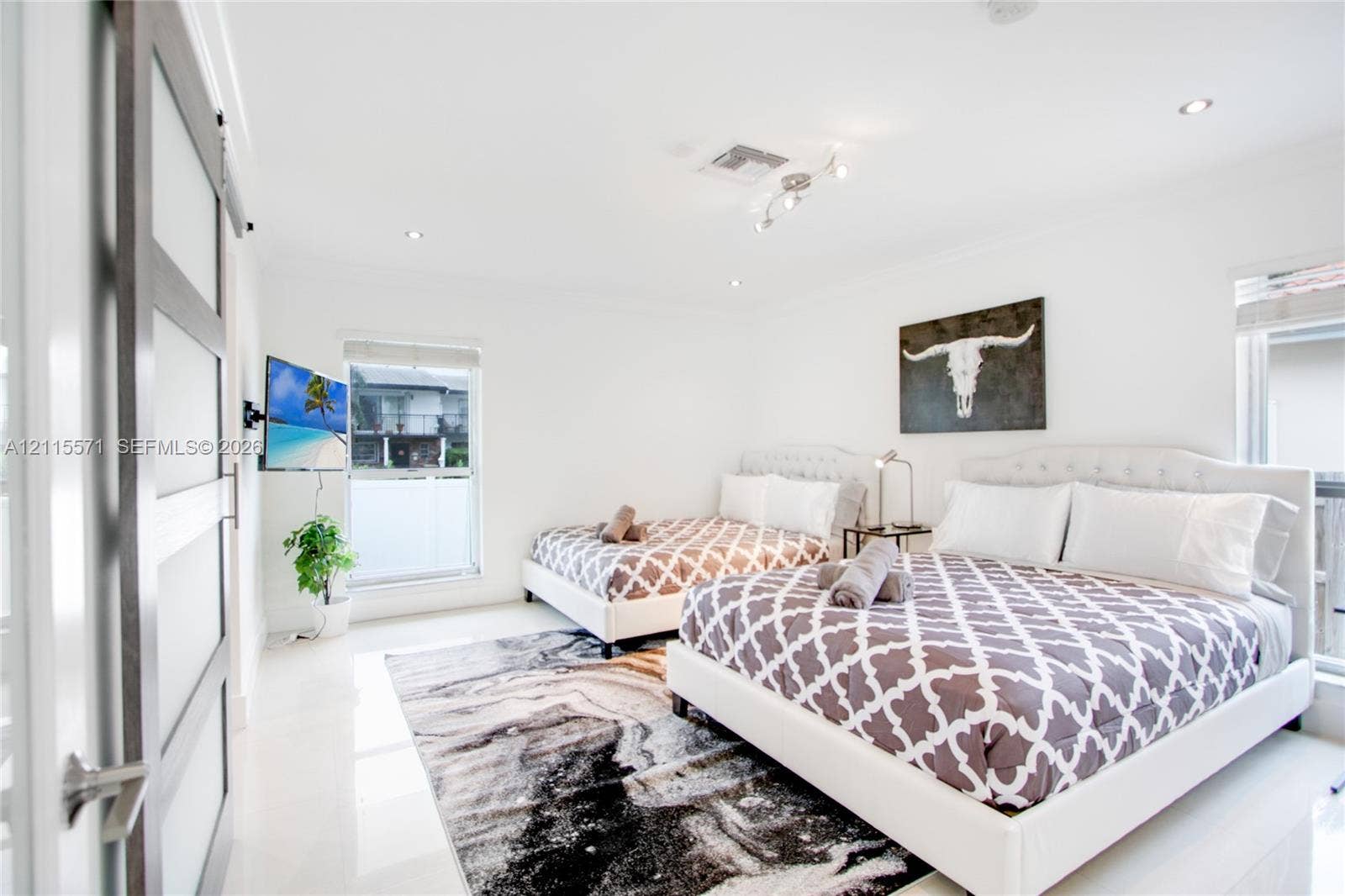 2001 NE 122nd Road, North Miami, FL 33181 Bedroom featuring recessed lighting, large-format tile flooring, and a sliding barn-style door with frosted glass panels