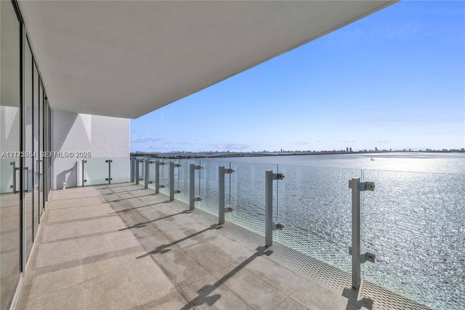 700 NE 26th Terrace, #901, Miami, Miami, FL 33137 Covered balcony with large-format tile flooring and floor-to-ceiling glass wall panels, featuring a frameless glass railing with metal posts