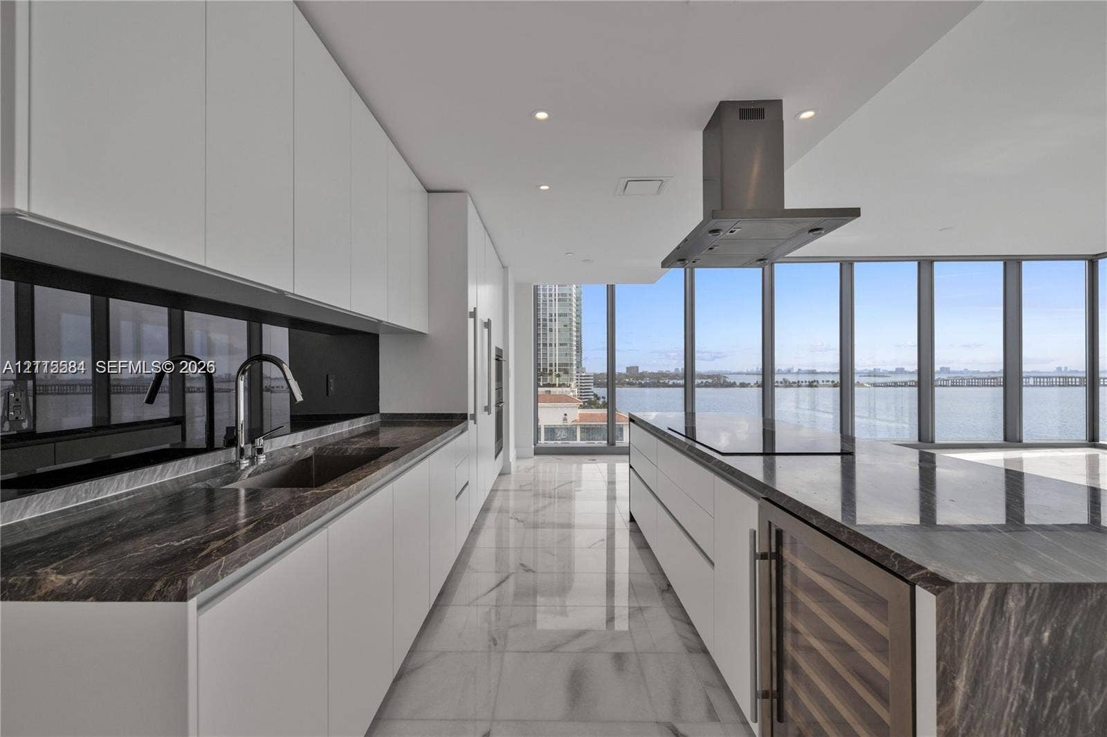 700 NE 26th Terrace, #901, Miami, Miami, FL 33137 Contemporary kitchen featuring white flat-panel cabinetry, stone countertops, integrated wine refrigeration, stainless steel vent hood, and floor-to-ceiling windows