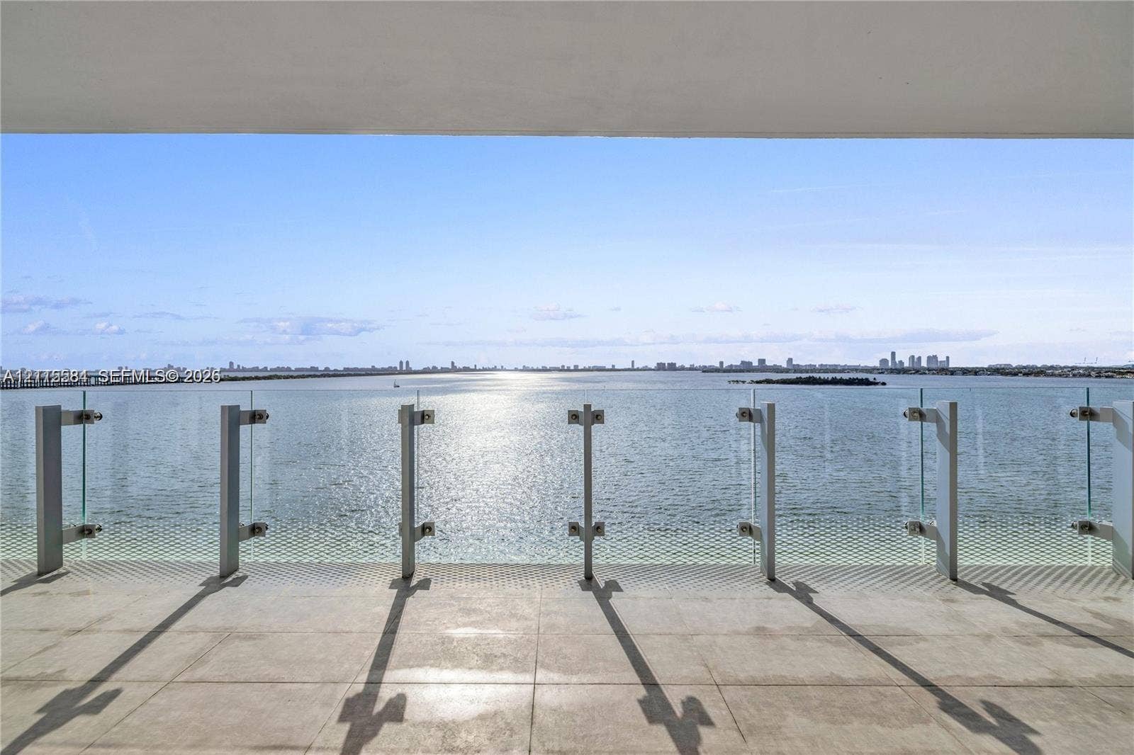 700 NE 26th Terrace, #901, Miami, Miami, FL 33137 Covered terrace featuring large-format stone flooring and a glass-panel railing overlooking the water and distant cityscape