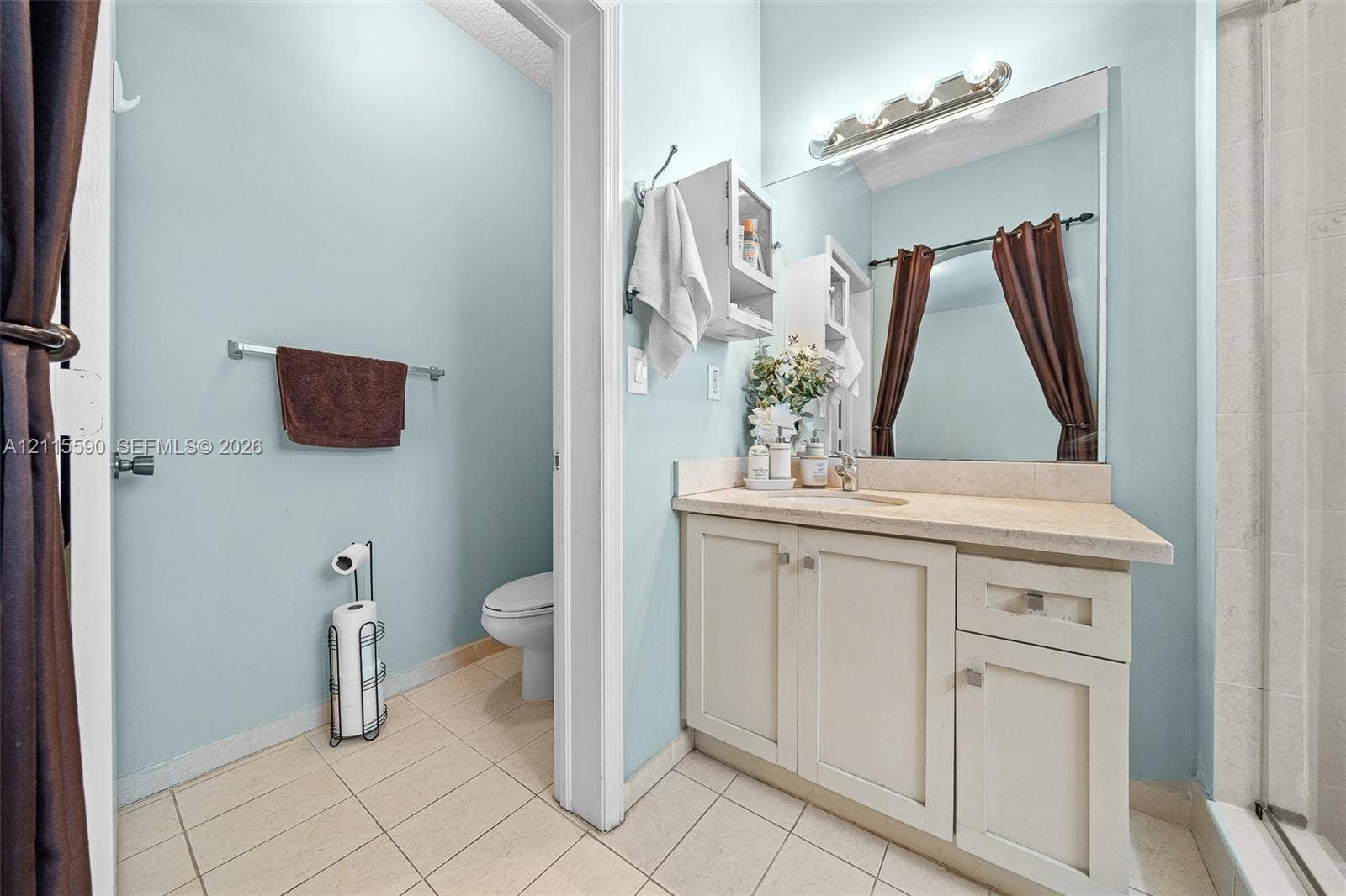 4948 Tradewinds Terrace, #504, Dania Beach, FL 33312 Bathroom featuring a vanity with light-toned cabinetry, solid surface countertop, integrated sink, wall-mounted light fixture, and tile flooring