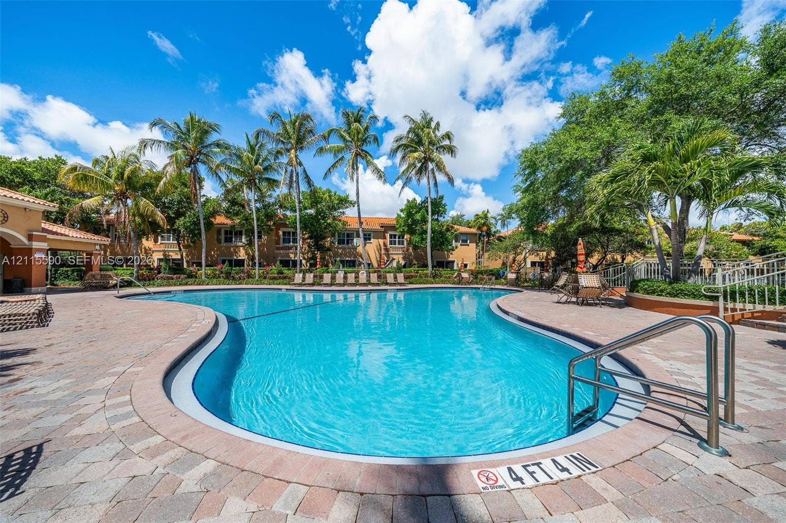 4948 Tradewinds Terrace, #504, Dania Beach, FL 33312 In-ground swimming pool featuring paver decking, metal entry rails, and surrounding palm trees