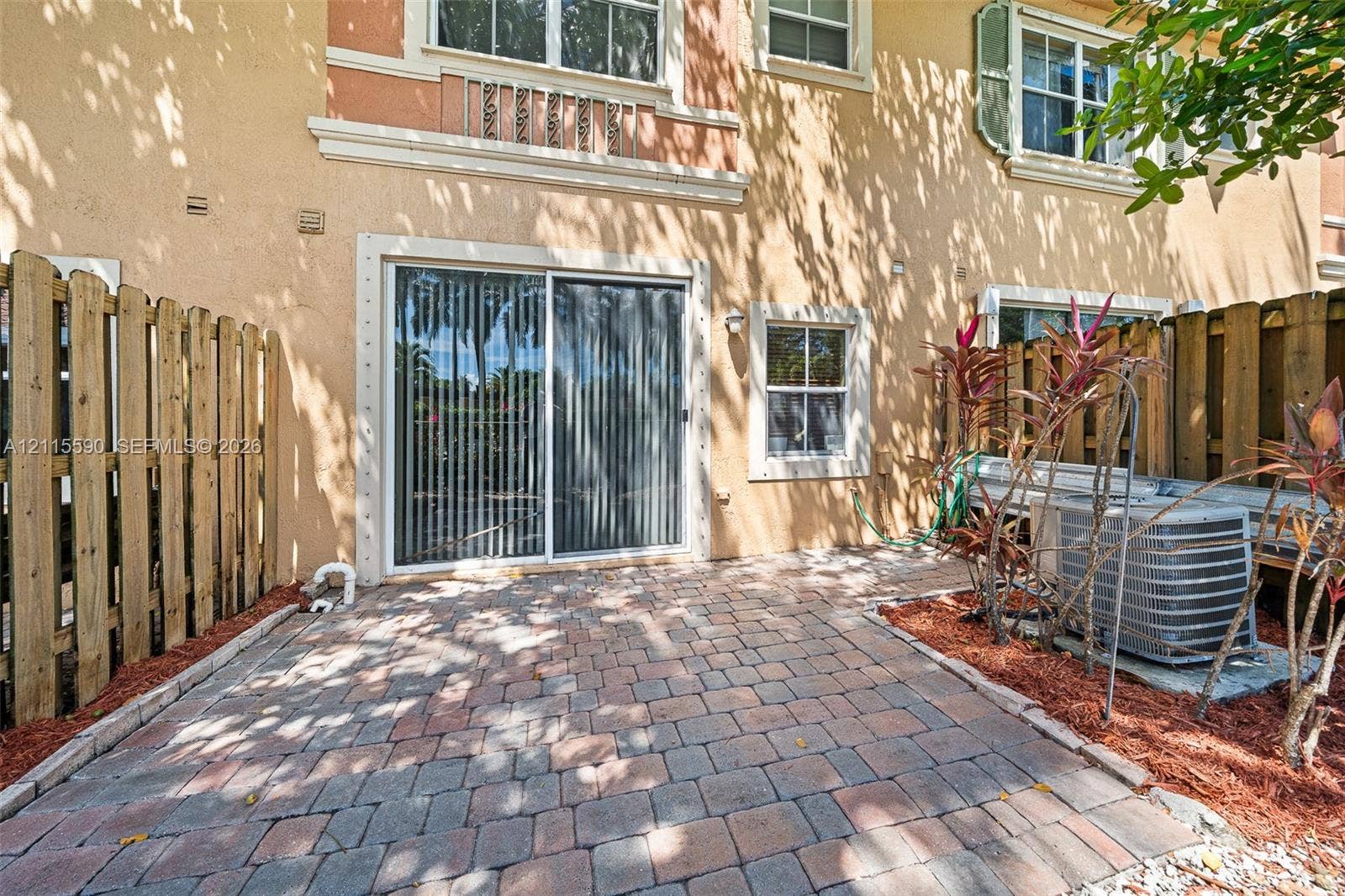 4948 Tradewinds Terrace, #504, Dania Beach, FL 33312 Private rear patio featuring stone paver flooring, enclosed by vertical wood privacy fencing and sliding glass doors