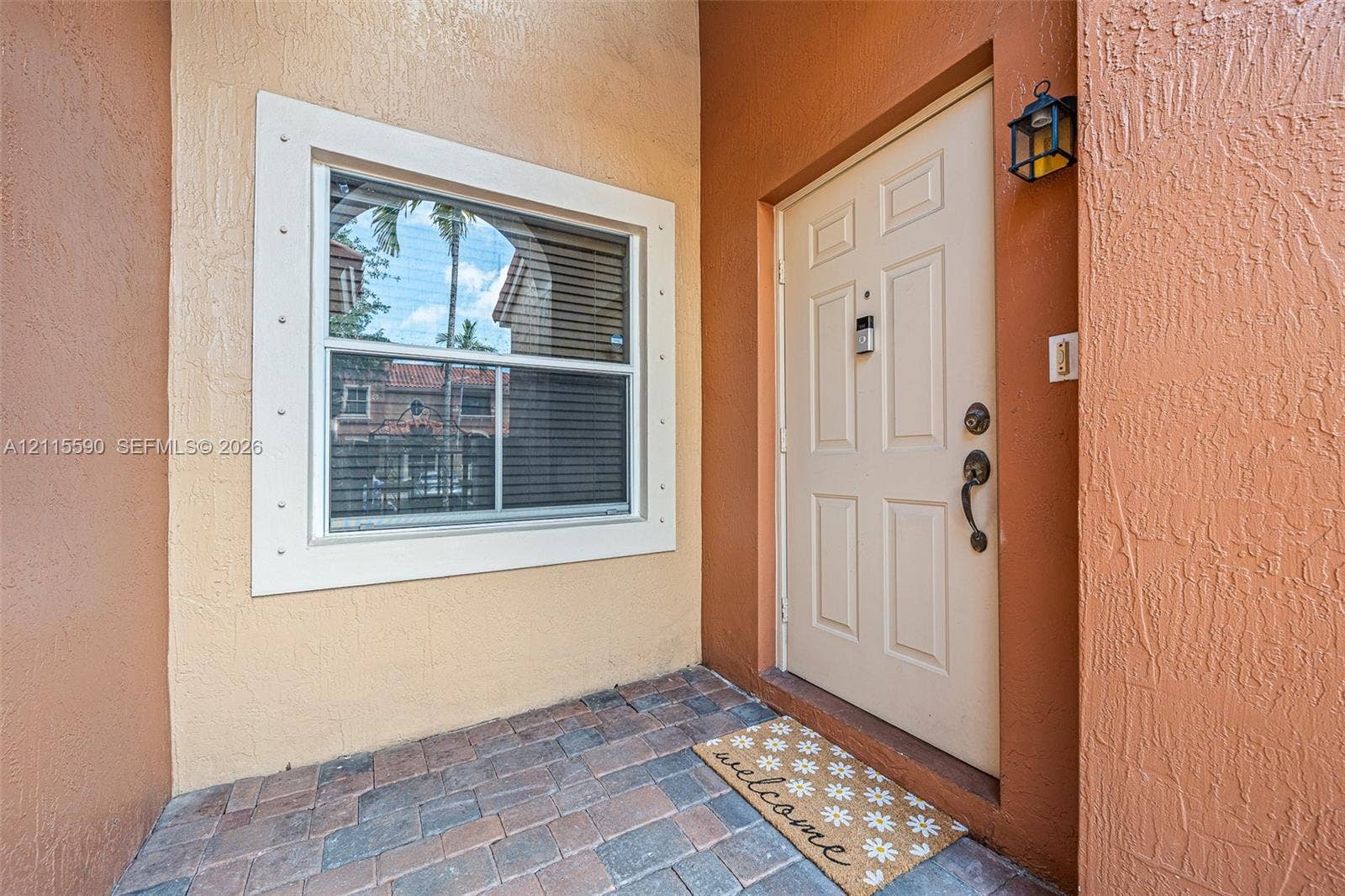 4948 Tradewinds Terrace, #504, Dania Beach, FL 33312 Entryway featuring a paver-stone landing, a six-panel exterior door with integrated hardware, and a window with a wide, custom-trimmed surround