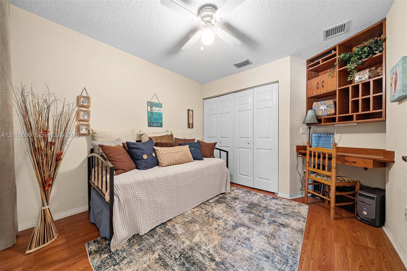 4948 Tradewinds Terrace, #504, Dania Beach, FL 33312 Wood-finish flooring, ceiling fan with integrated light fixture, built-in wooden desk with overhead shelving, and double-door closet