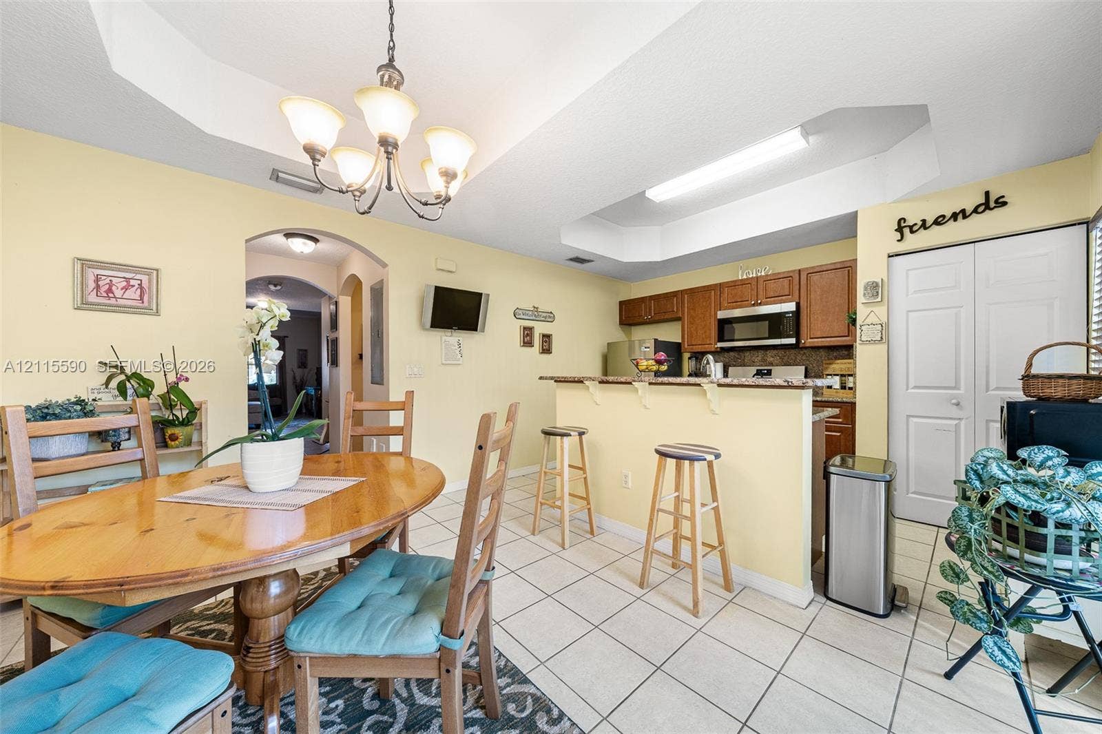 4948 Tradewinds Terrace, #504, Dania Beach, FL 33312 Kitchen featuring a breakfast bar, recessed tray ceiling, tile flooring, and wood cabinetry