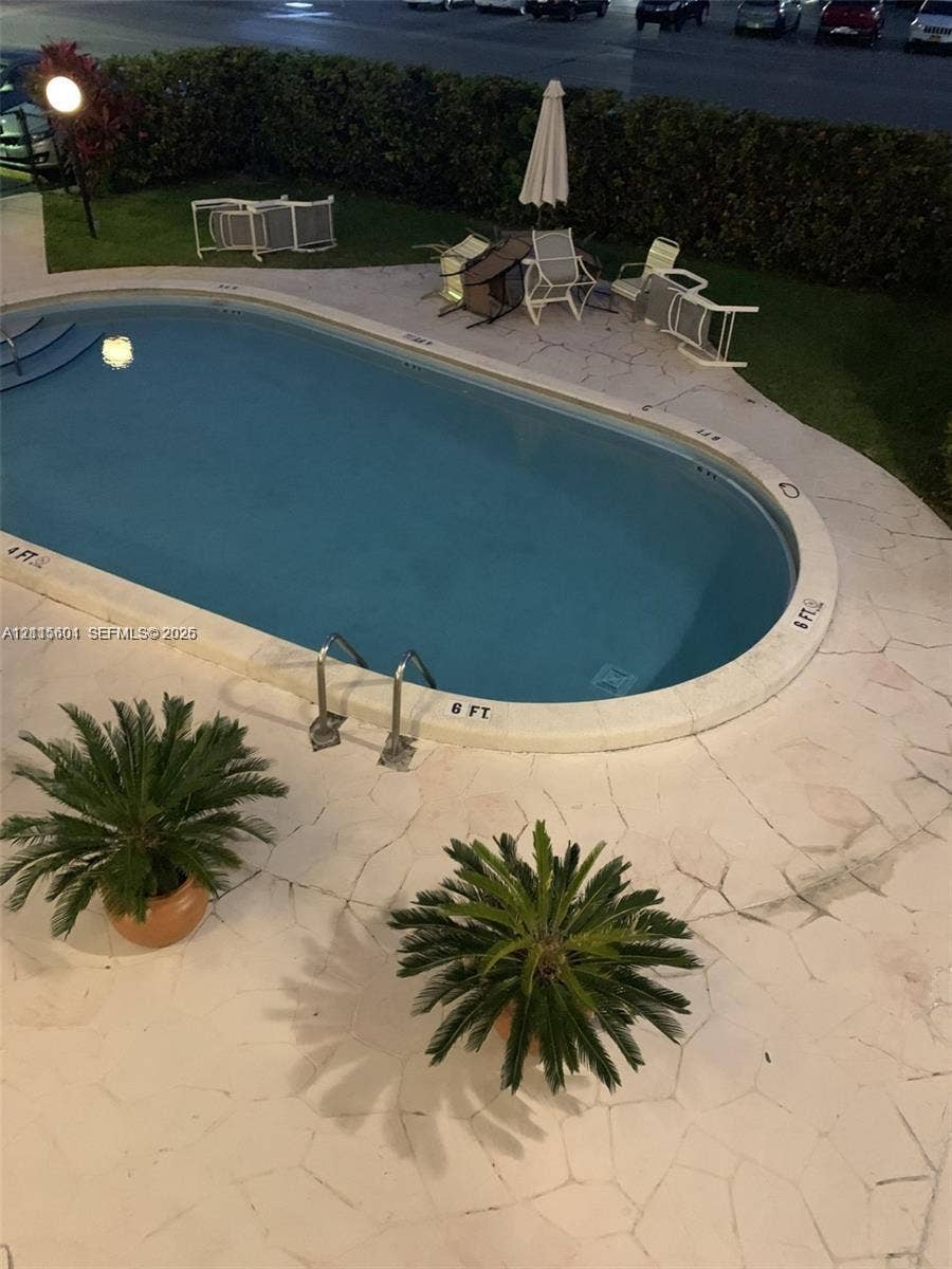 Oval swimming pool featuring metal ladders, integrated steps, and light-toned flagstone hardscaping