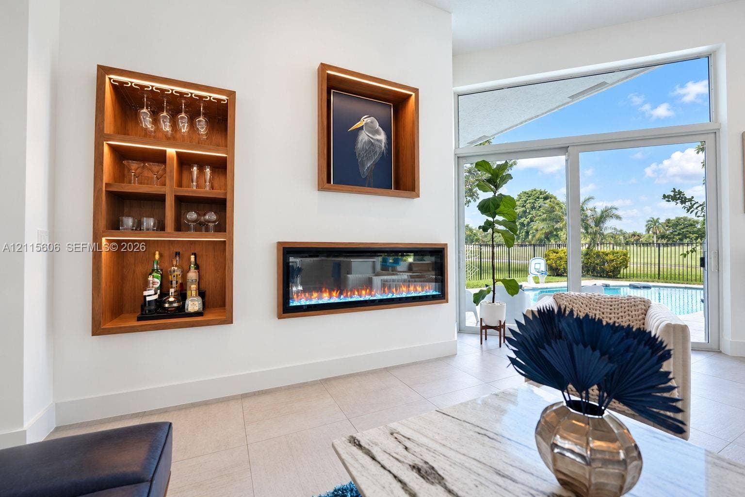 2652 Palmer Place, #2652, Weston, Weston, FL 33332 Built-in illuminated wood shelving, recessed linear electric fireplace, large-format tile flooring, and floor-to-ceiling sliding glass doors with outdoor pool exposure