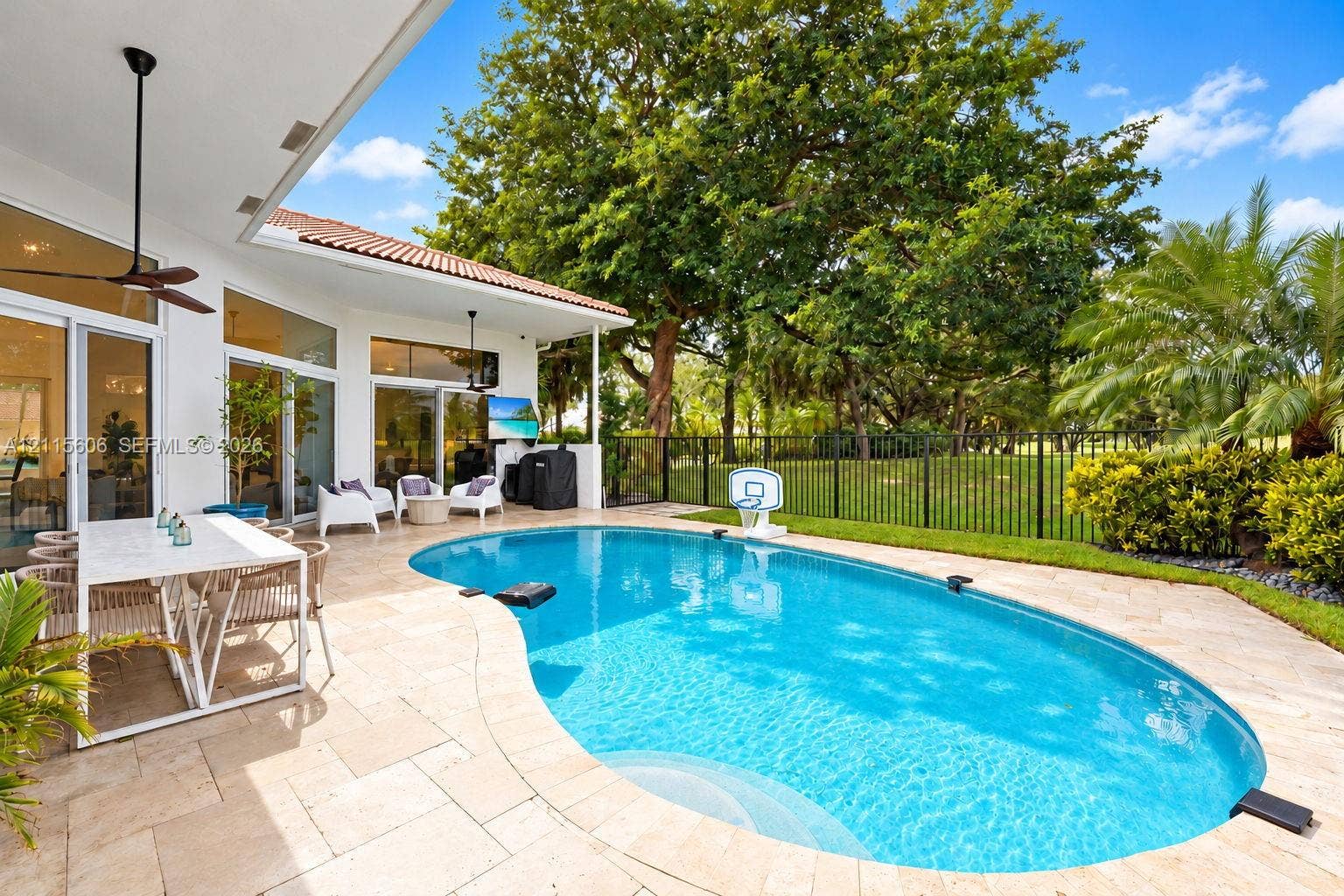2652 Palmer Place, #2652, Weston, Weston, FL 33332 Covered outdoor patio featuring stone pavers, a kidney-shaped in-ground swimming pool, metal perimeter fencing, and floor-to-ceiling glass panel doors