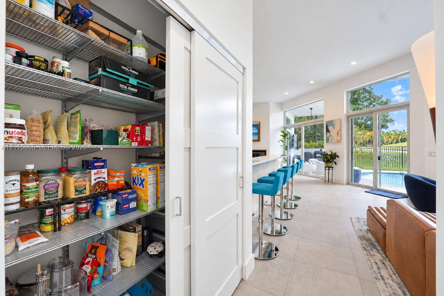 2652 Palmer Place, #2652, Weston, Weston, FL 33332 Walk-in pantry featuring adjustable wire shelving and a sliding shaker-style door, highlighted by neutral tile flooring, recessed lighting, and expansive floor-to-ceiling glass sliding doors