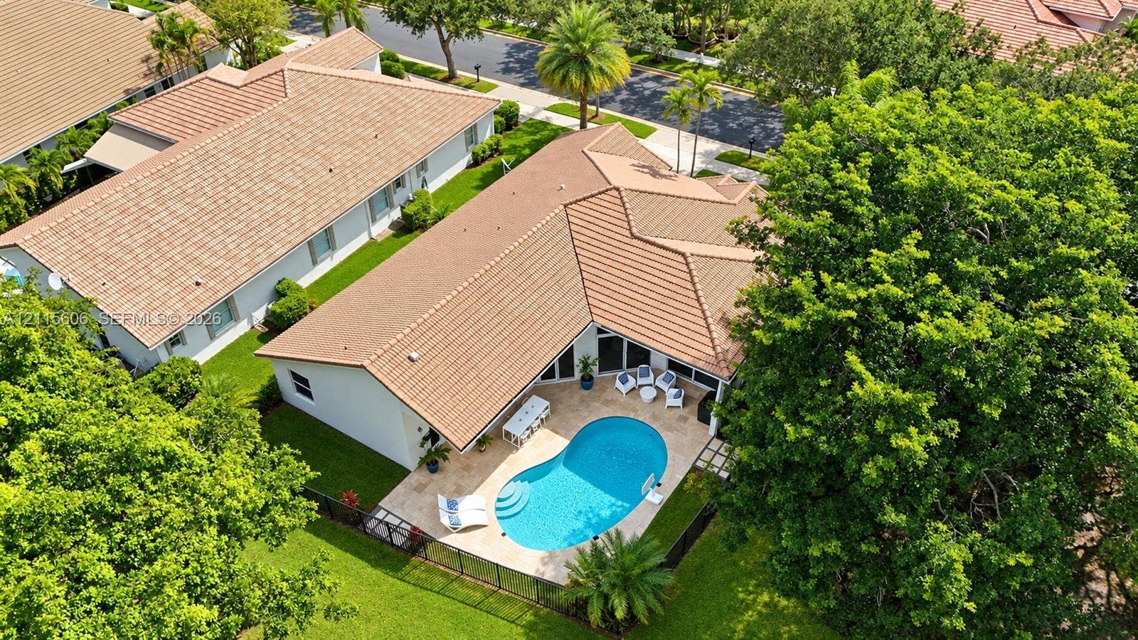 2652 Palmer Place, #2652, Weston, Weston, FL 33332 Aerial perspective of a residence featuring a clay tile roof, a private swimming pool with built-in entry steps, a stone-paved patio, and a fenced yard with mature trees