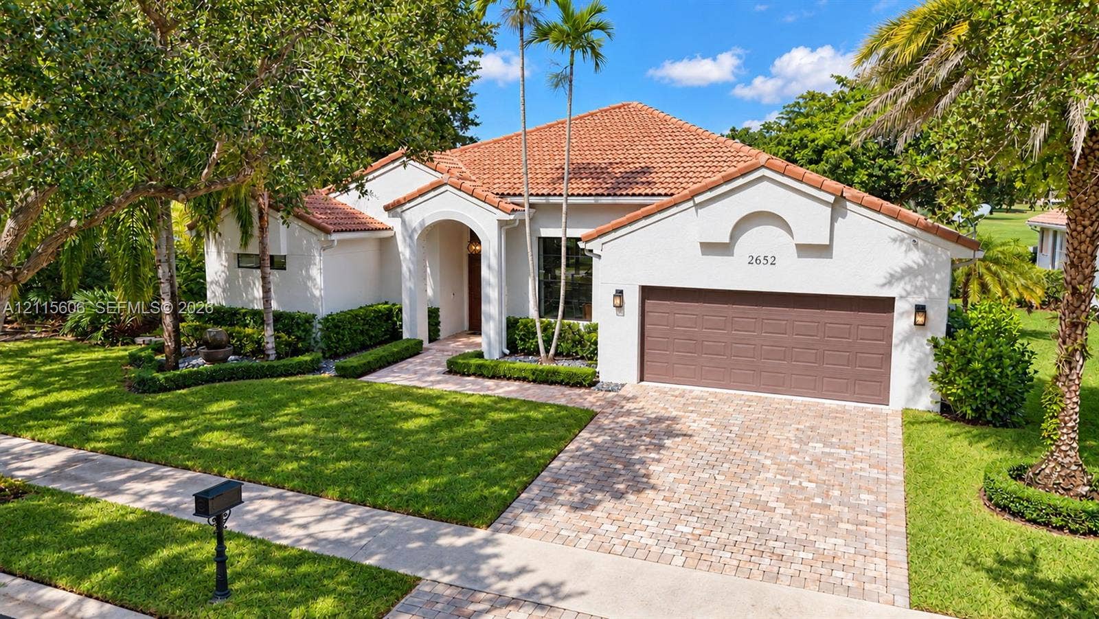 2652 Palmer Place, #2652, Weston, Weston, FL 33332 Stucco exterior featuring a red tile roof, arched entryway, paved driveway, and curated landscaping