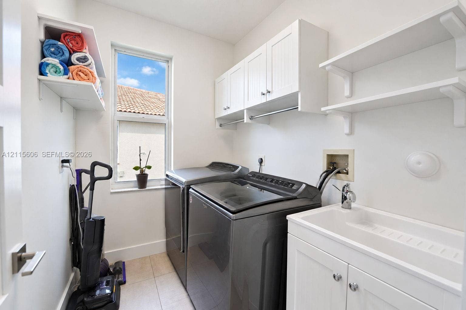 2652 Palmer Place, #2652, Weston, Weston, FL 33332 Laundry room featuring white shaker-style cabinetry, open wall shelving, a built-in utility sink with a chrome faucet, and tile flooring