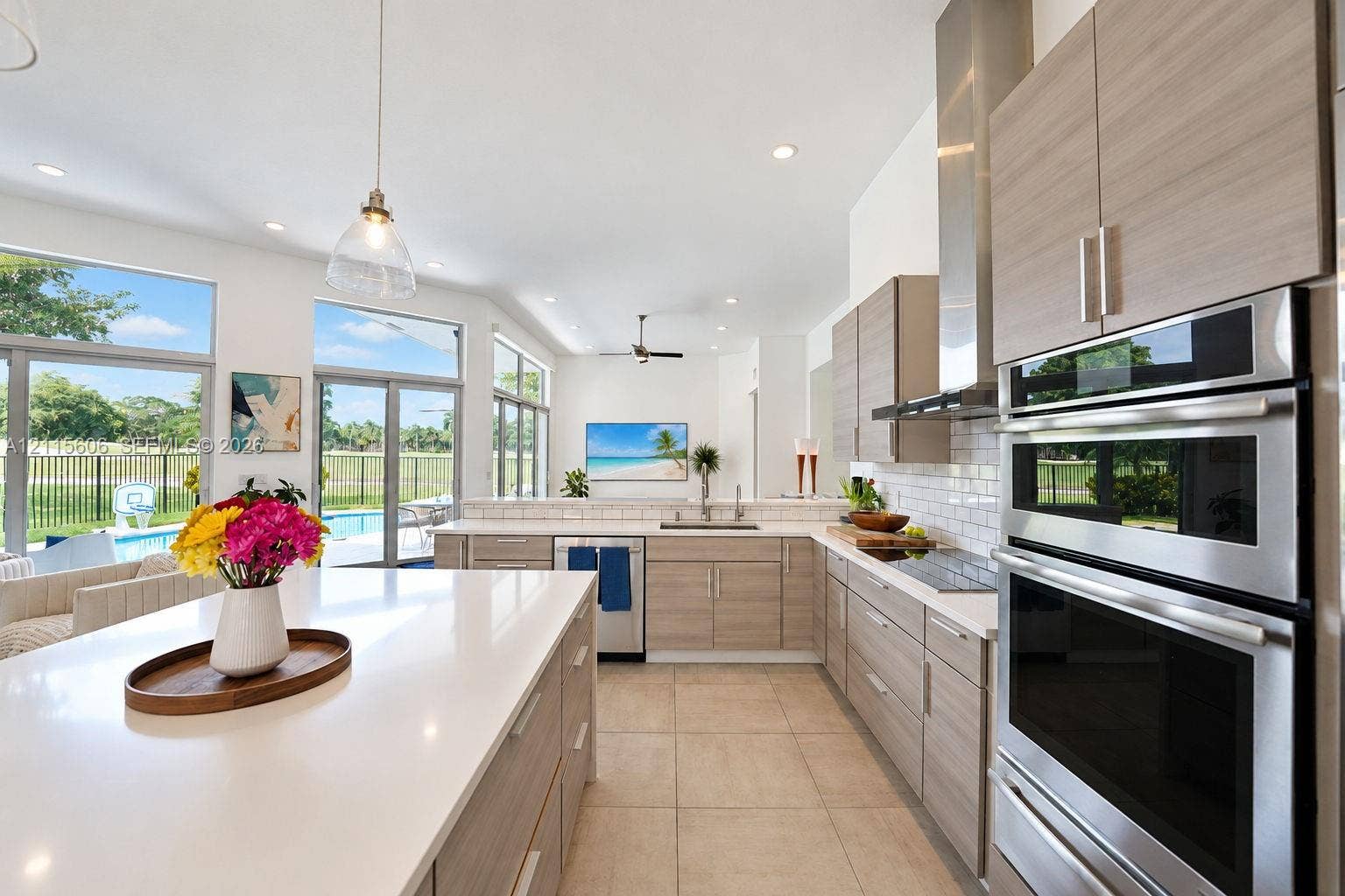 2652 Palmer Place, #2652, Weston, Weston, FL 33332 Kitchen featuring a large central island with a quartz countertop, wood-finish cabinetry, stainless steel double wall ovens, a white subway tile backsplash, and floor-to-ceiling windows