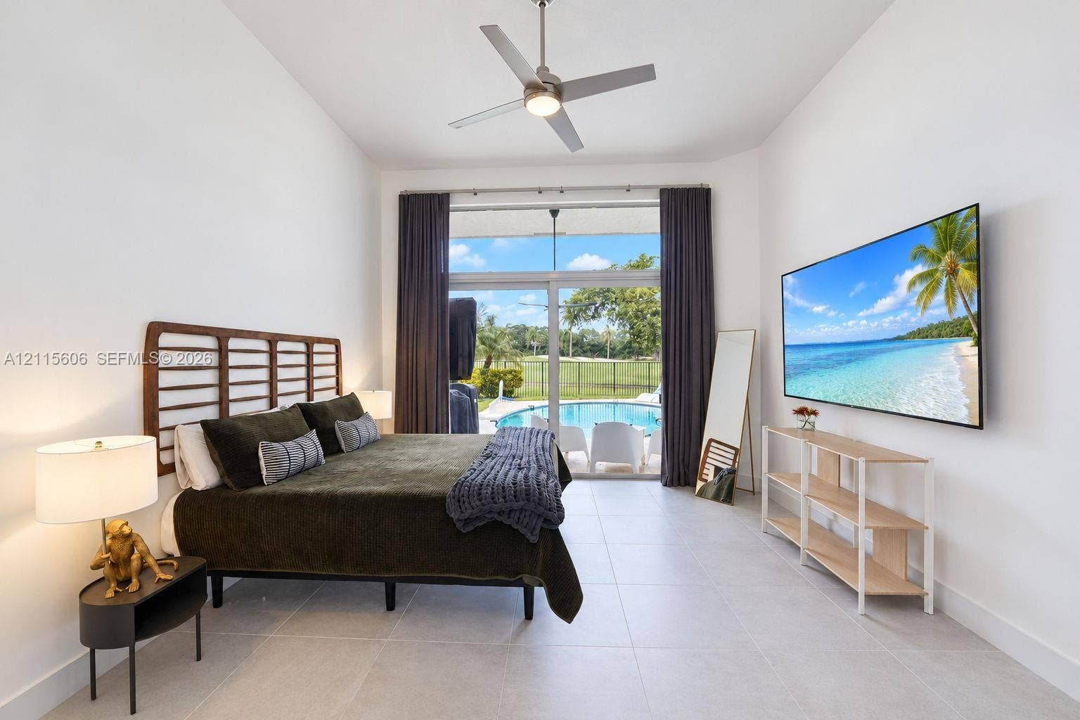 2652 Palmer Place, #2652, Weston, Weston, FL 33332 High-ceilinged room featuring large-format tile flooring, a brushed metal ceiling fan, and floor-to-ceiling sliding glass doors opening to an exterior swimming pool and patio area