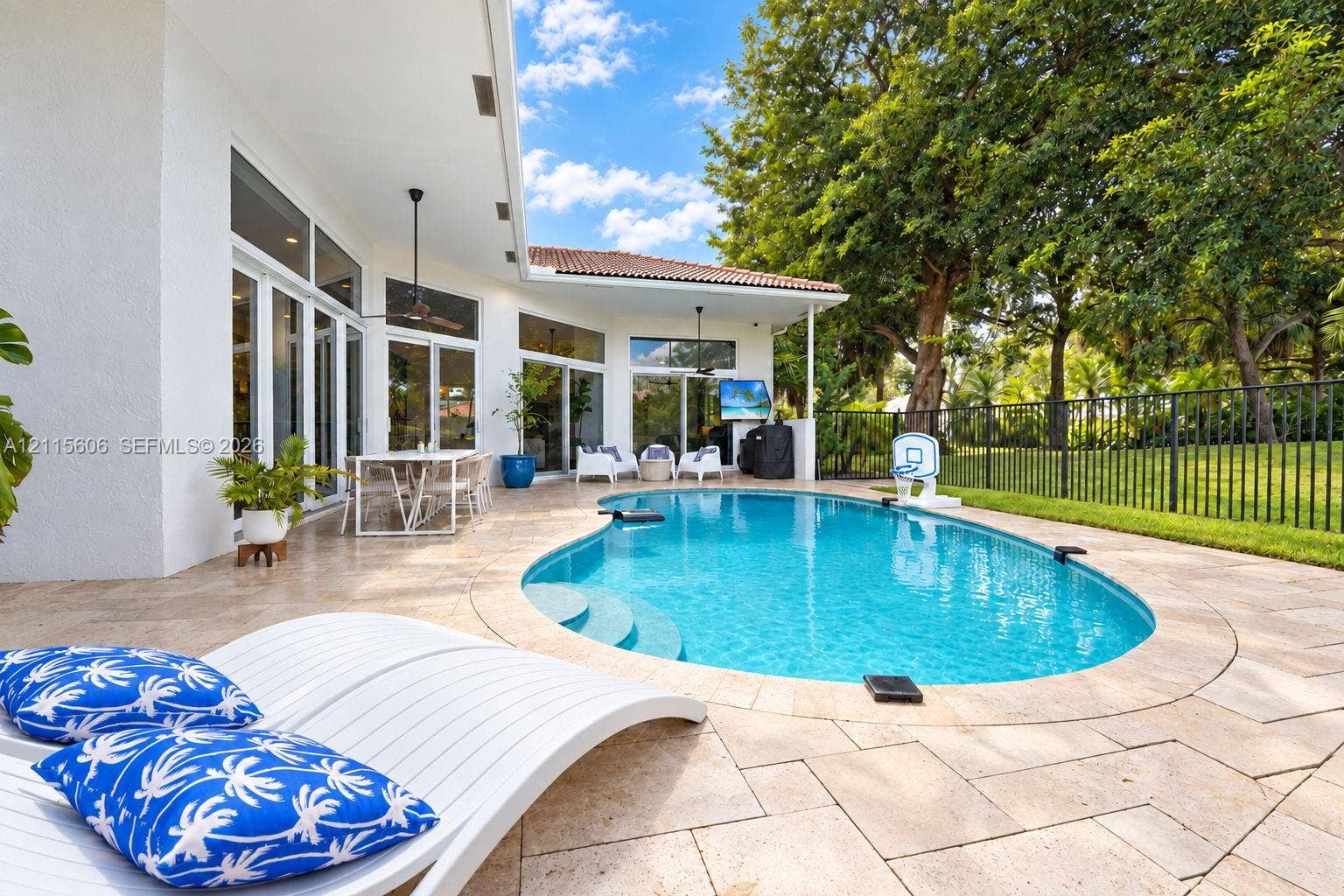 2652 Palmer Place, #2652, Weston, Weston, FL 33332 Outdoor patio featuring natural stone pavers, a custom-shaped swimming pool with integrated steps, a covered lanai with ceiling fans, and black metal perimeter fencing