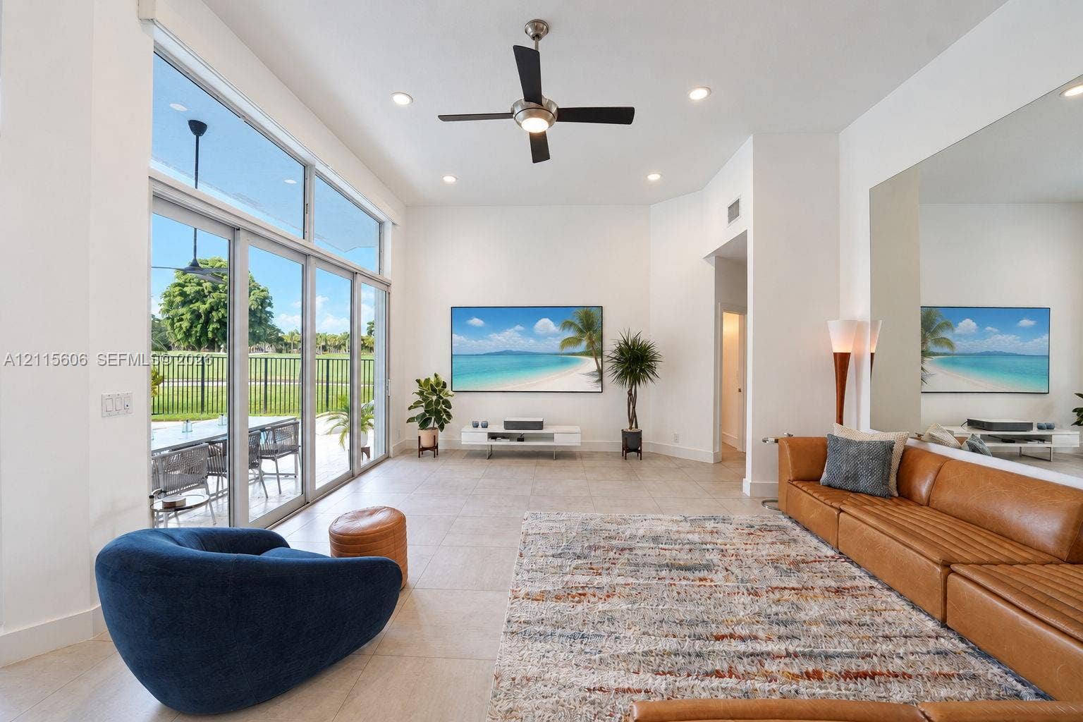 2652 Palmer Place, #2652, Weston, Weston, FL 33332 High-ceiling living space featuring floor-to-ceiling glass sliding doors, large-format tile flooring, a mounted ceiling fan with integrated lighting, and a full-length wall mirror