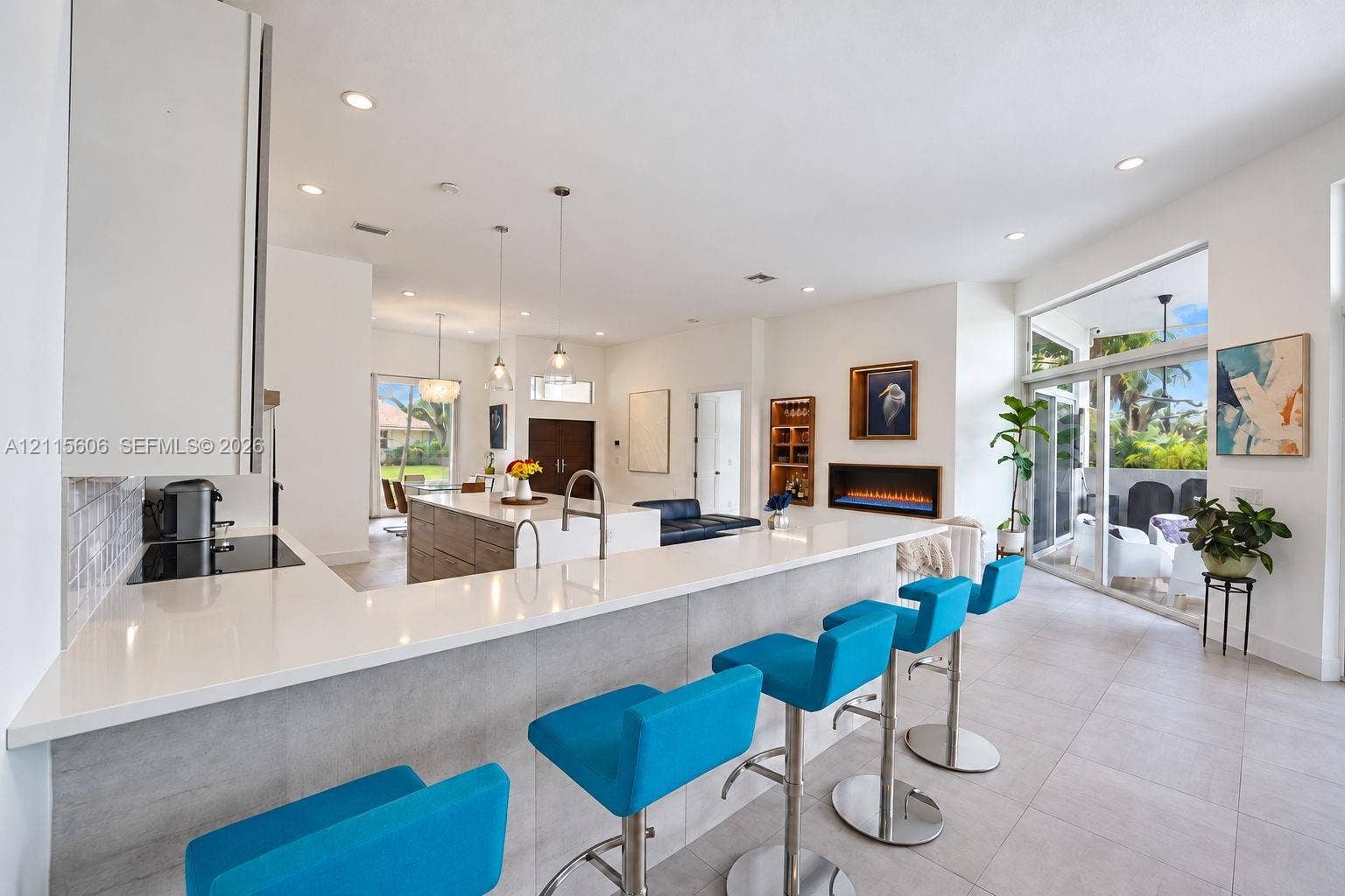 2652 Palmer Place, #2652, Weston, Weston, FL 33332 Kitchen featuring an extended quartz countertop island, built-in cabinetry, flush-mounted lighting, and a linear wall-recessed fireplace