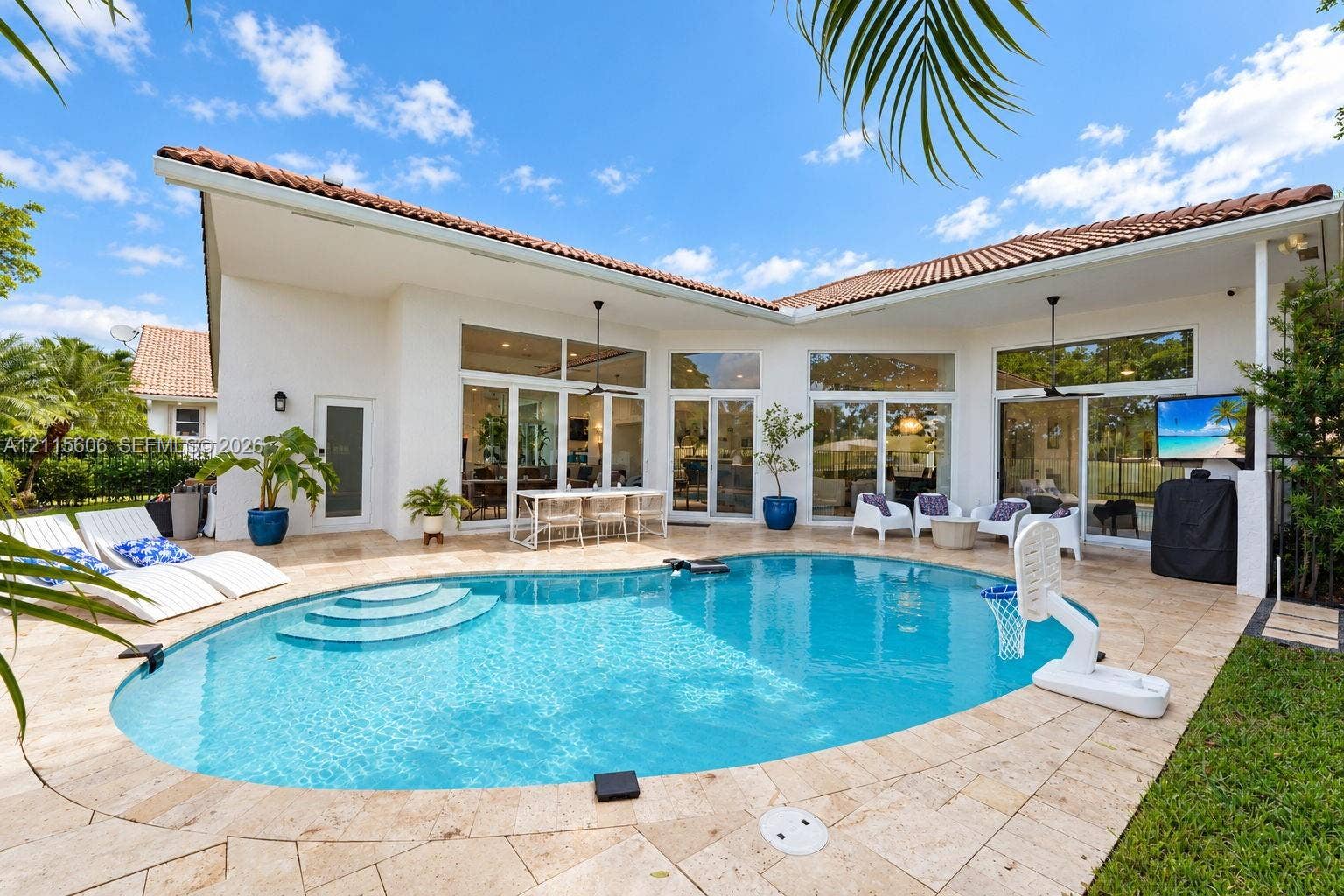 2652 Palmer Place, #2652, Weston, Weston, FL 33332 Outdoor living area featuring a custom-shaped swimming pool with built-in steps, expansive stone paver patio, covered loggia, and large-scale glass sliding doors
